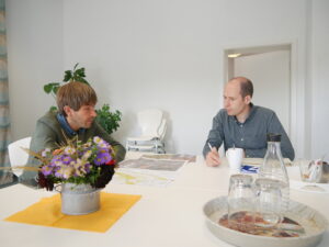 Bürgermeister Nierhoff und Tim Pargent sitzen an einem Tisch und reden