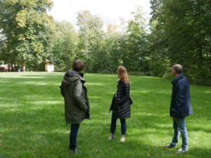 Drei Menschen stehen auf einer grünen Wiese